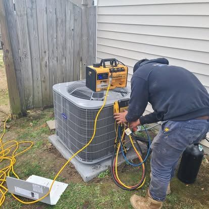 HVAC technician servicing an air conditioning unit outside, connecting gauges, using tools.