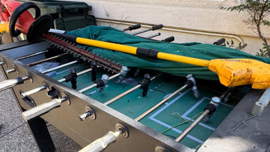 Folded outdoor golf putting green and practice net with poles and clamps on the ground