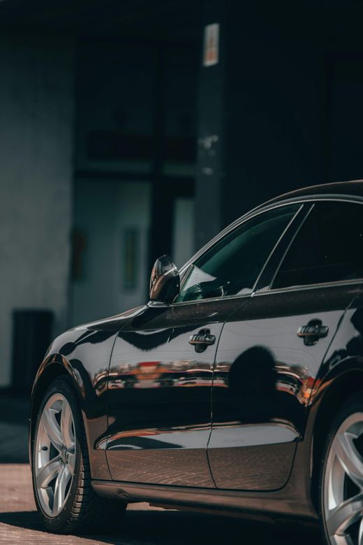 Berlina nera parcheggiata di notte con il braccio di una persona che sporge dal finestrino del guidatore.