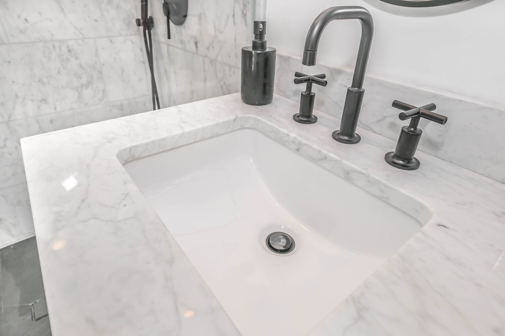 Ceramic sink with a sleek gray stainless steel faucet.