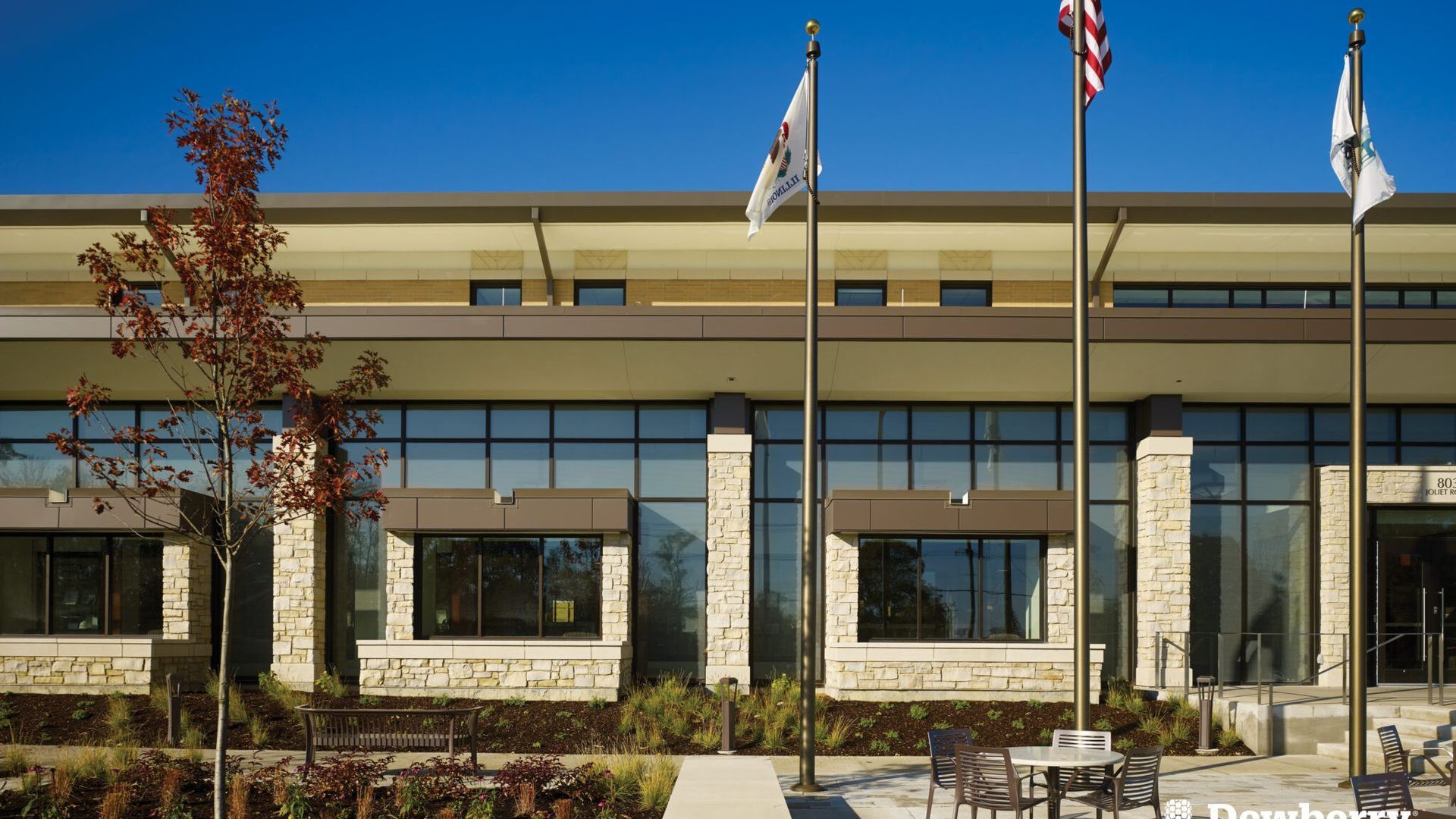 Three flags are flying in front of a large building