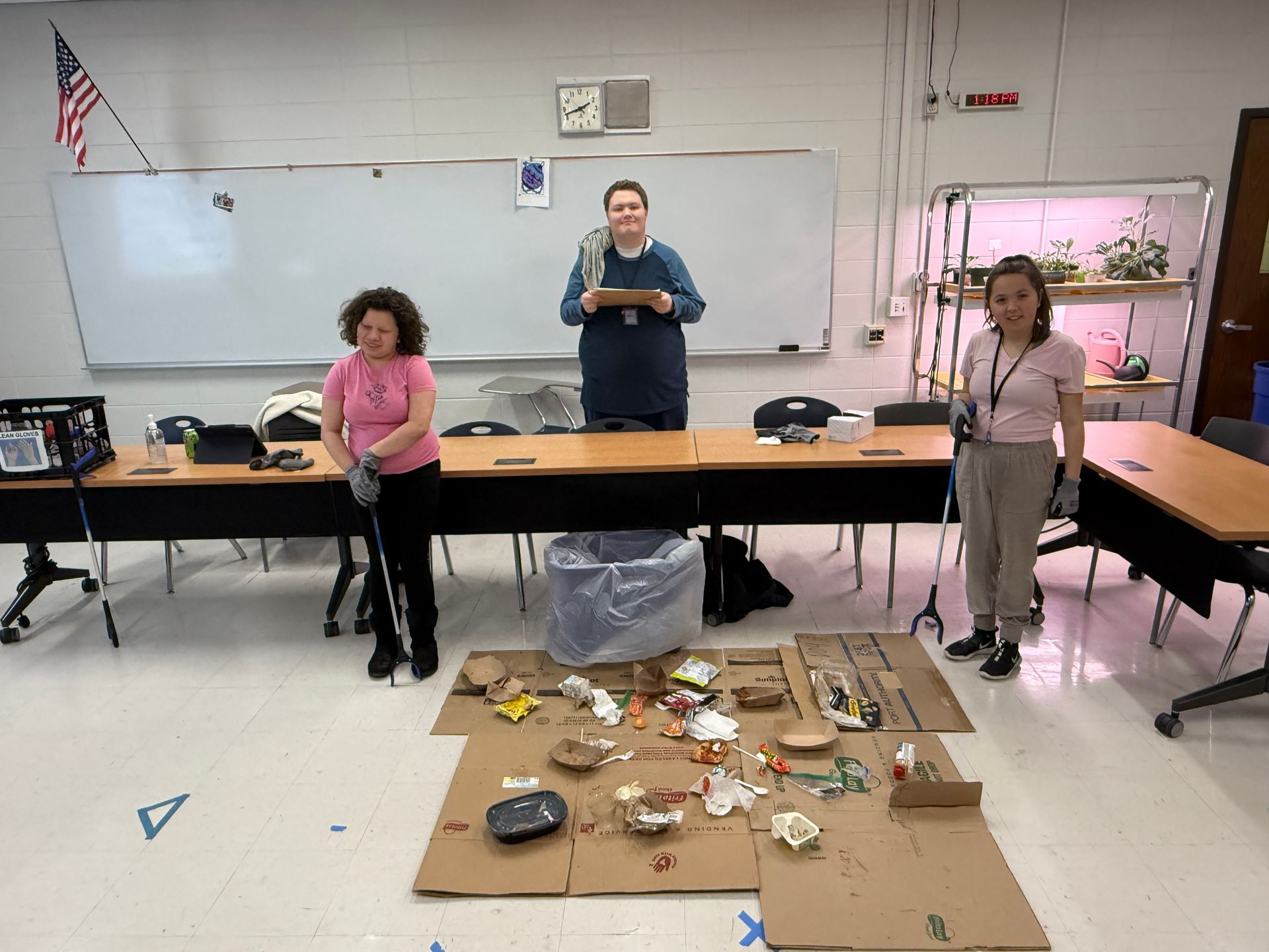 A man and a woman are standing in front of a whiteboard in a classroom.