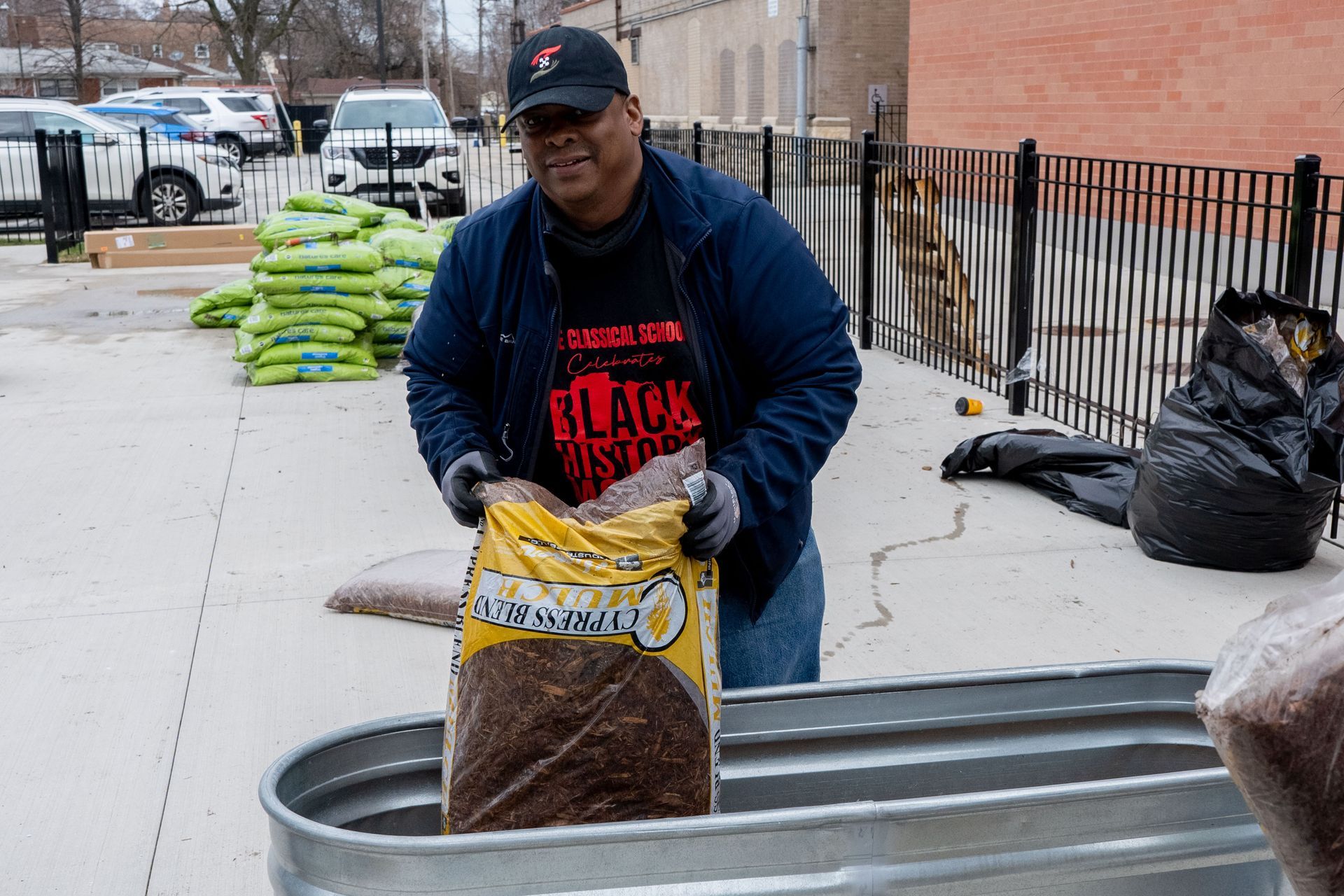 A man is carrying a bag of dirt into a metal tub.