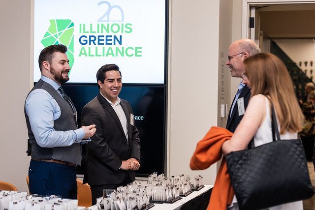 A group of people are standing in front of a sign that says illinois green alliance.