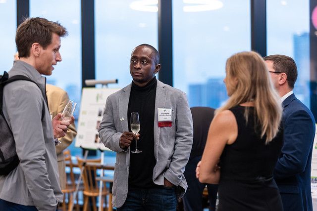 A group of people are standing in a room talking to each other.