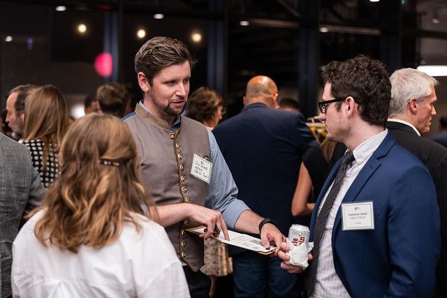 A group of people are standing in a room talking to each other.