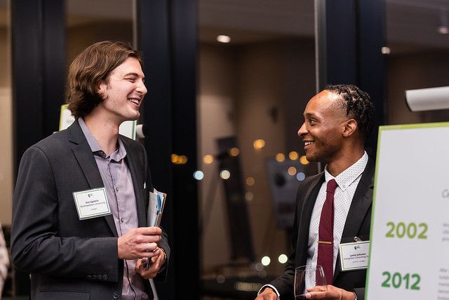 Two men in suits and ties are standing next to each other and talking.