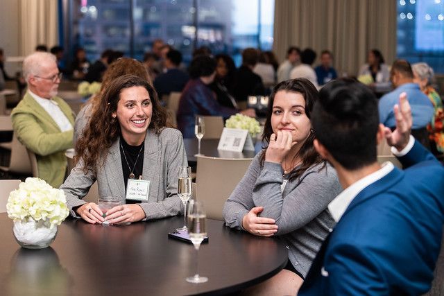 A group of people are sitting at a table talking to each other.