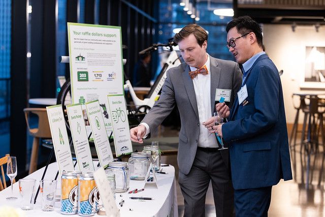 Two men in suits are standing next to each other at a table.