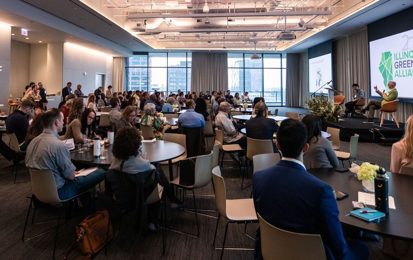 A large group of people are sitting at tables in a conference room.