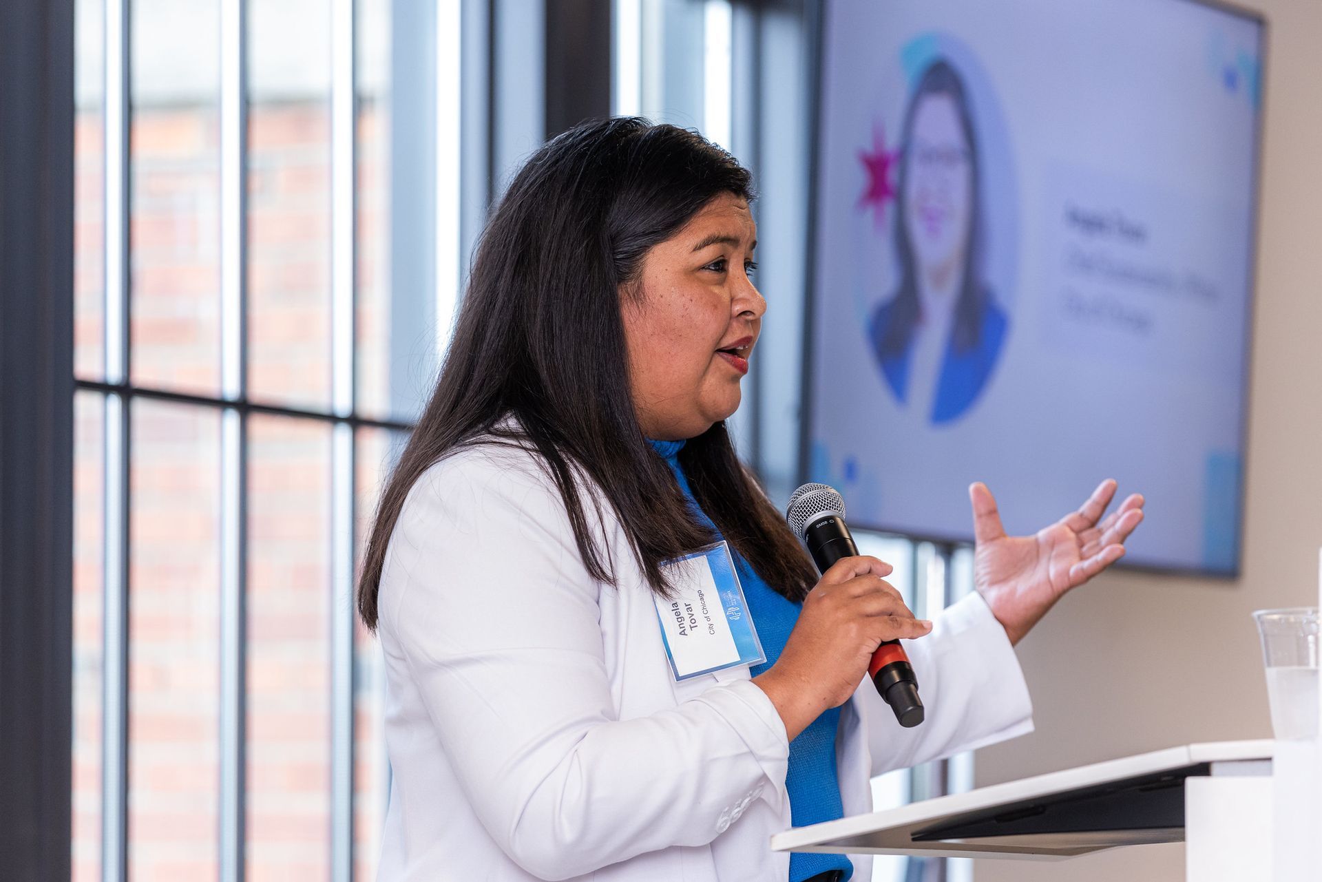 A woman is standing at a podium holding a microphone.