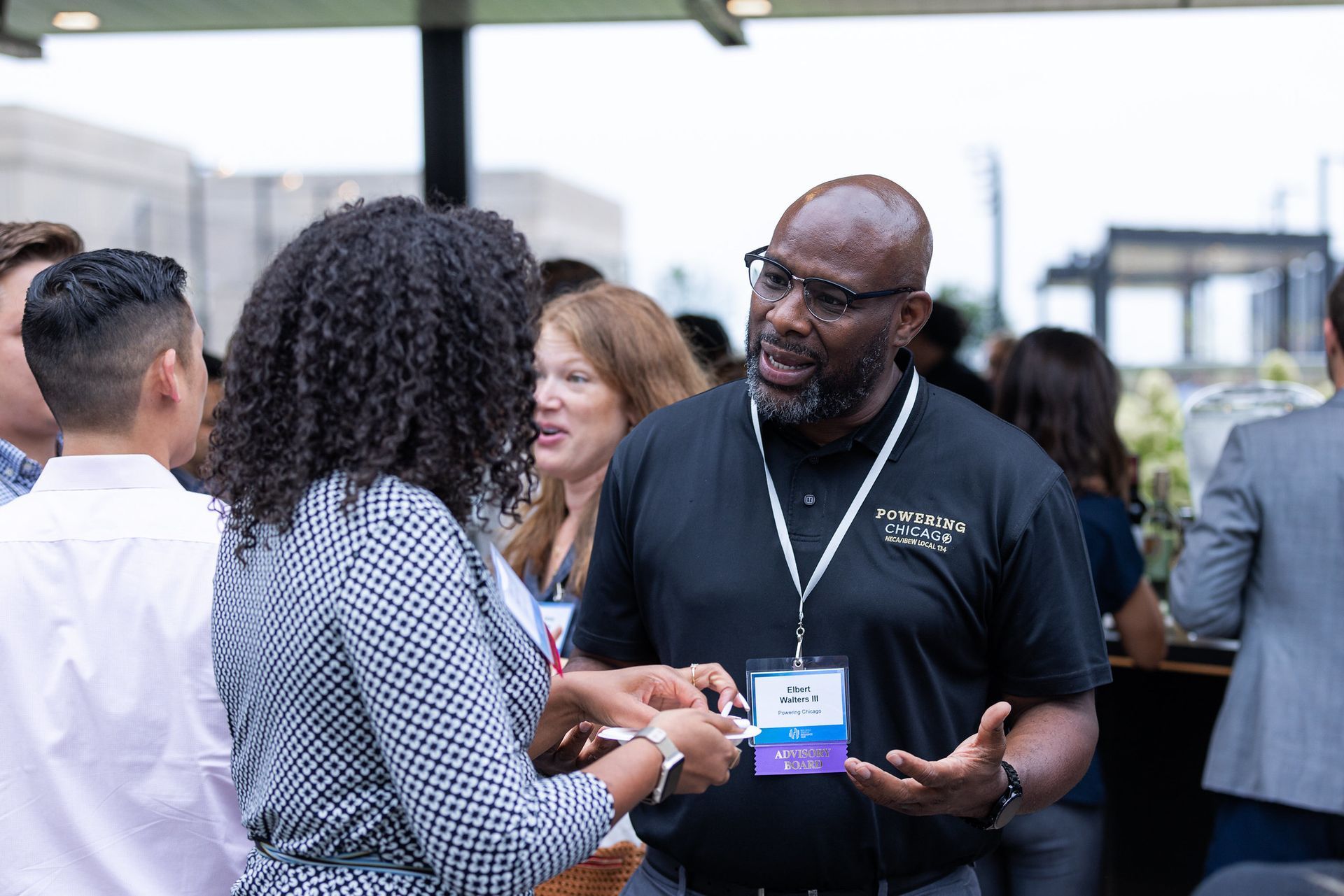 A group of people are standing around a table talking to each other.