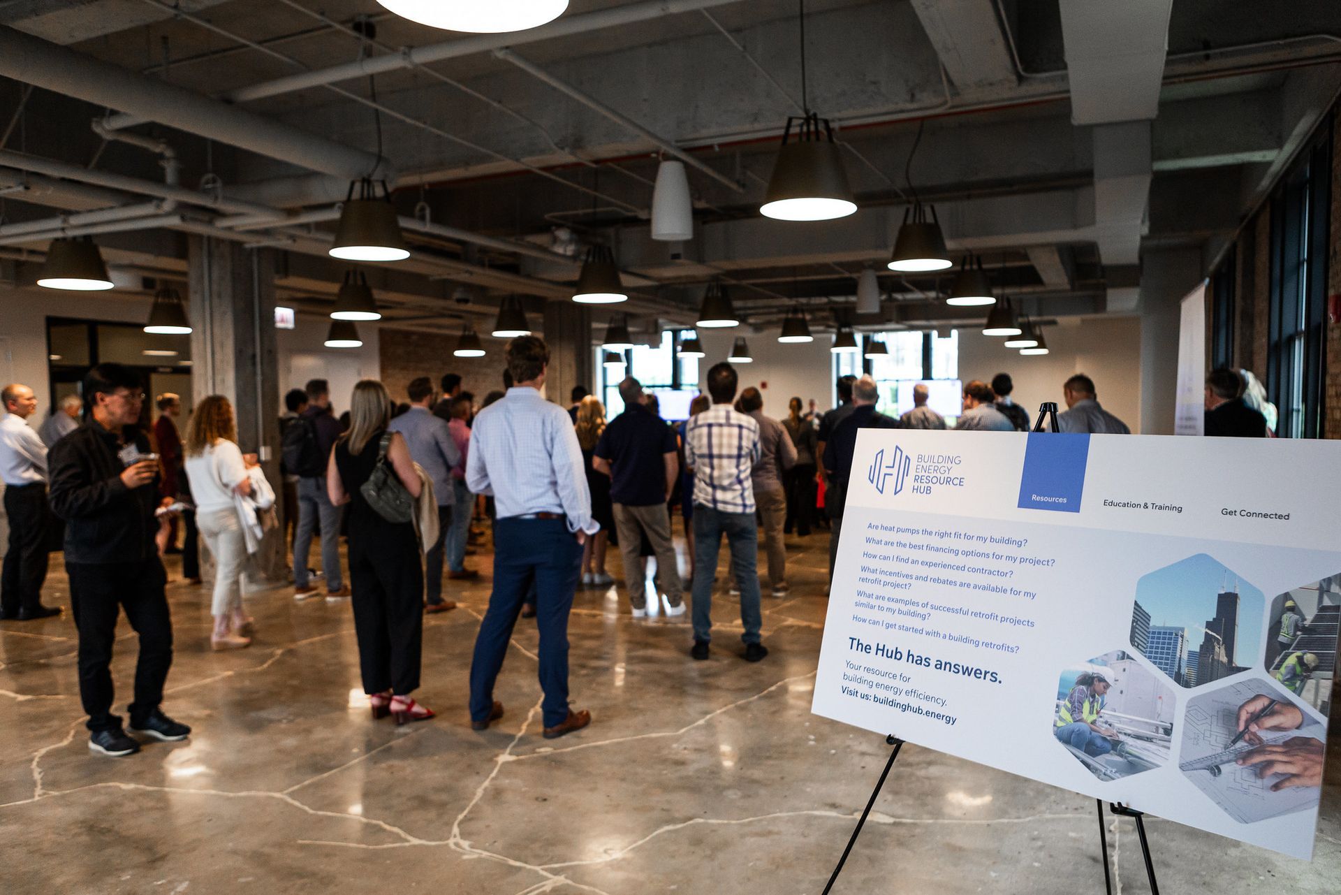 A group of people are standing around a sign in a large room.