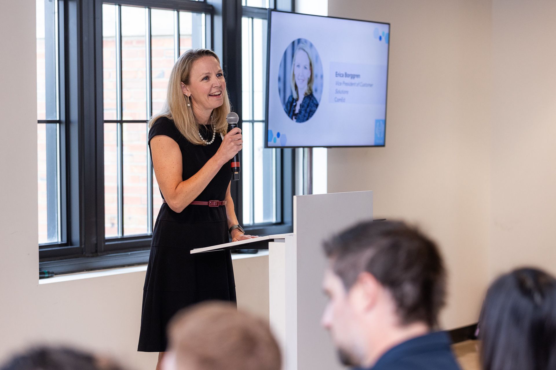 A woman is standing at a podium giving a presentation to a group of people.
