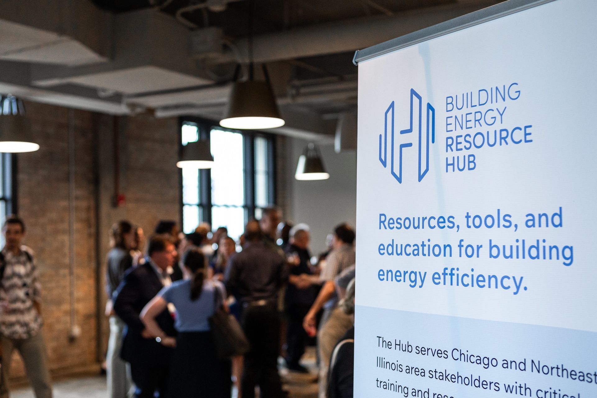 A group of people are standing around a sign that says building energy resource hub.