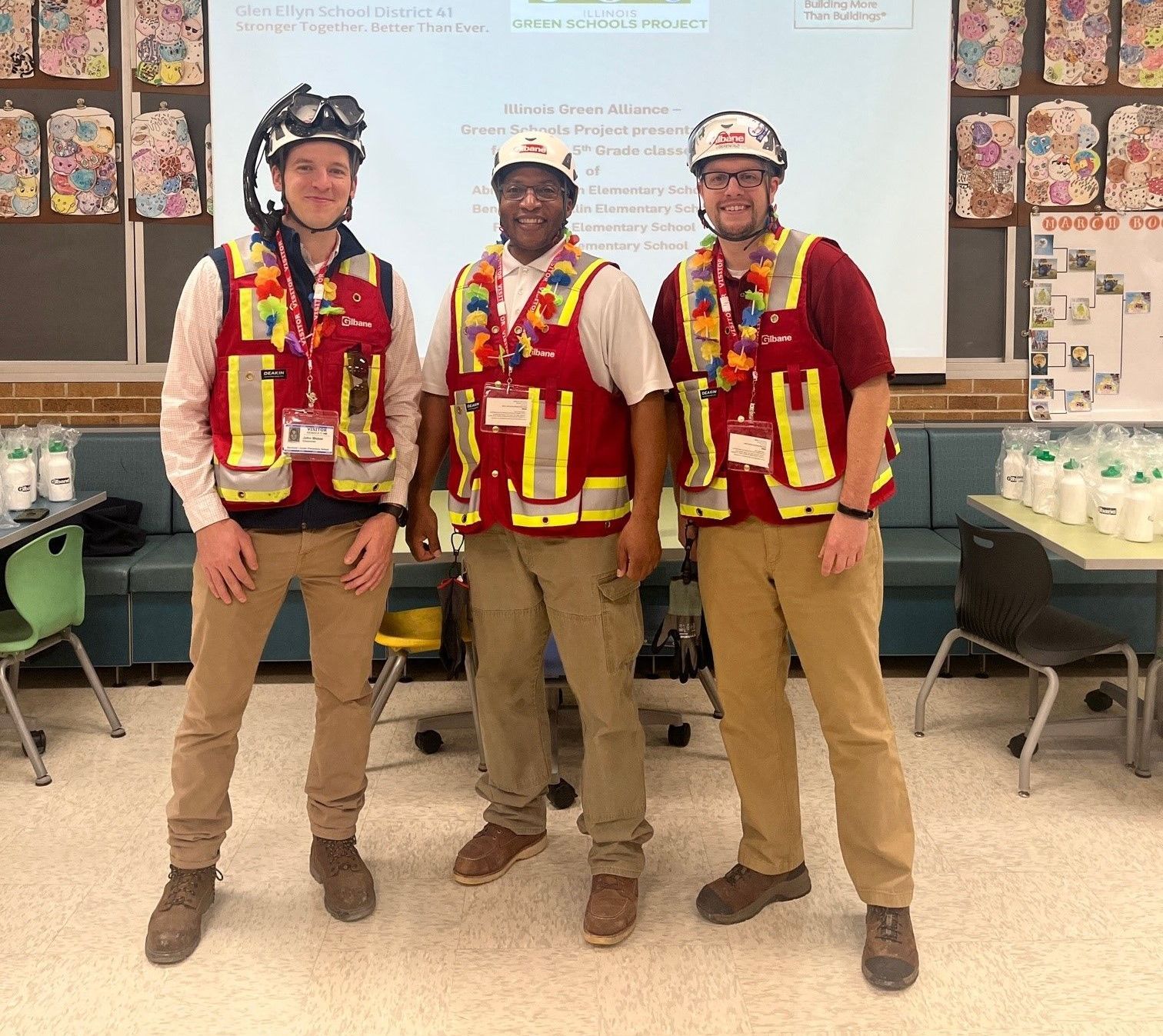 Three men wearing safety vests and hard hats pose for a picture