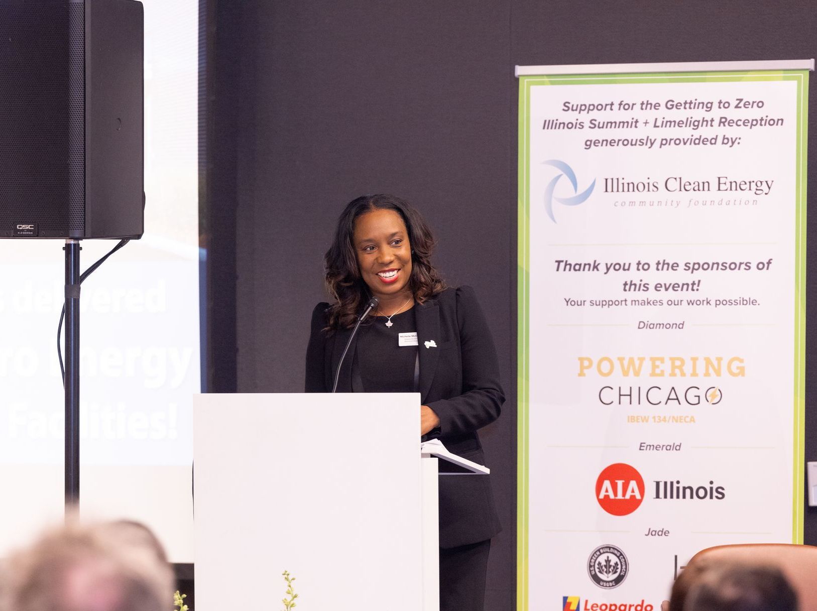A woman is giving a speech at a podium in front of a sign that says powering chicago