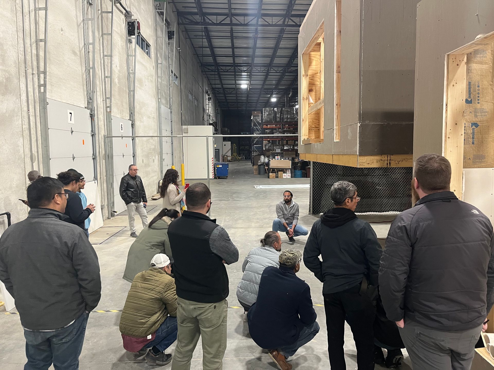 A group of people are standing in a warehouse looking at a fireplace.