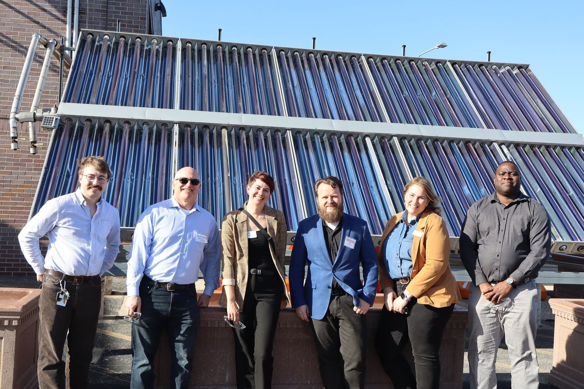 A group of people standing in front of a solar panel.