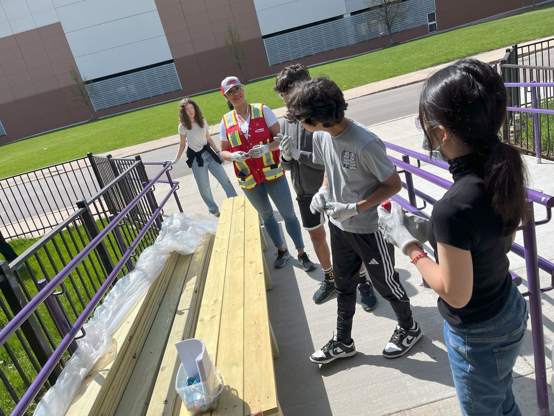 A group of people are standing around a wooden plank.