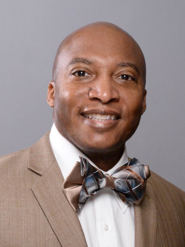 A man in a suit and bow tie smiles for the camera