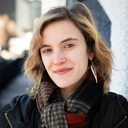 A woman with short blonde hair is smiling and wearing a black tank top