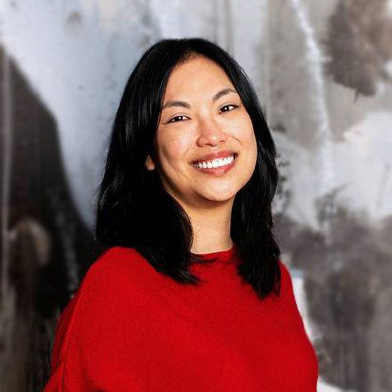A woman in a red shirt is smiling for the camera.