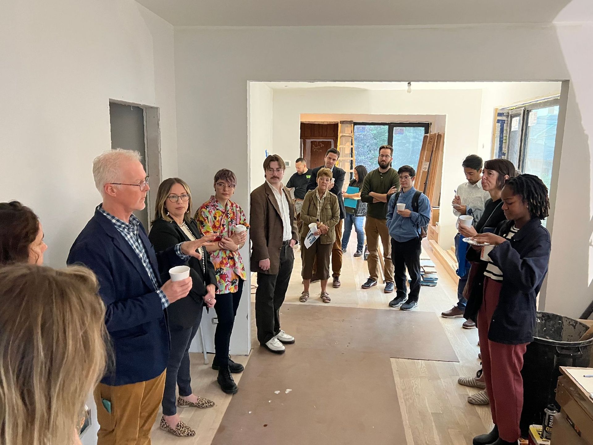 A group of people are standing in a room talking to each other.