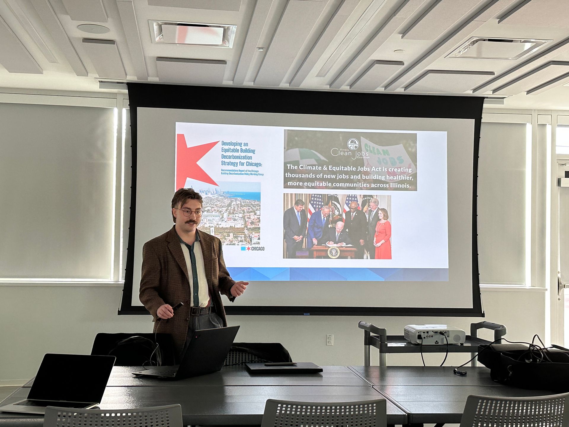 A man is giving a presentation in front of a large screen.