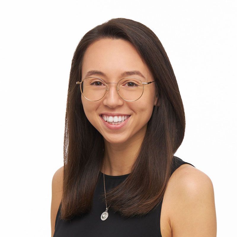 A woman wearing glasses and a black tank top smiles for the camera