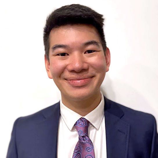 A young man in a suit and tie is smiling for the camera.