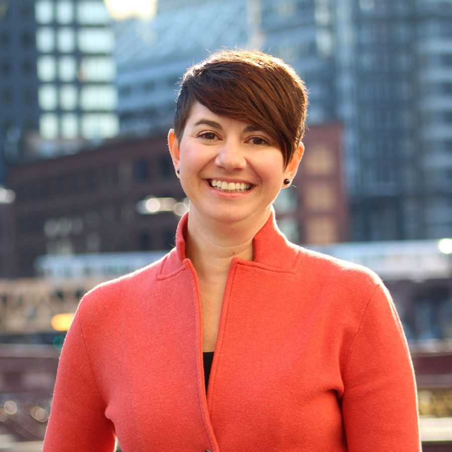 A woman in a red jacket is smiling for the camera