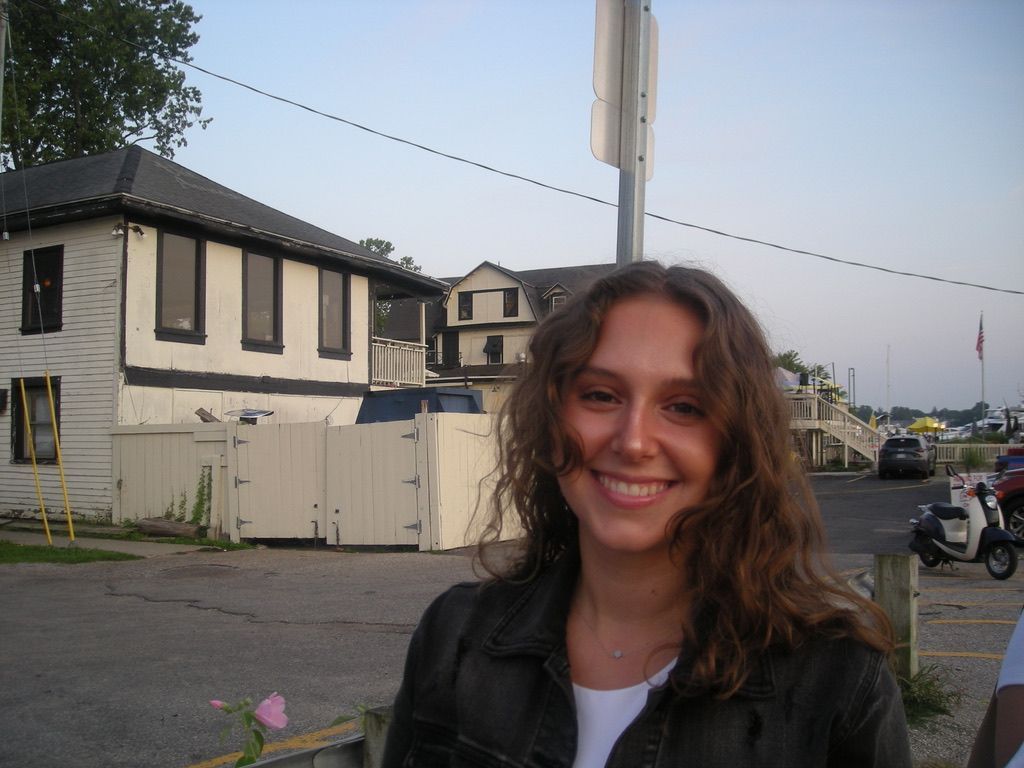 A woman is smiling in front of a white house