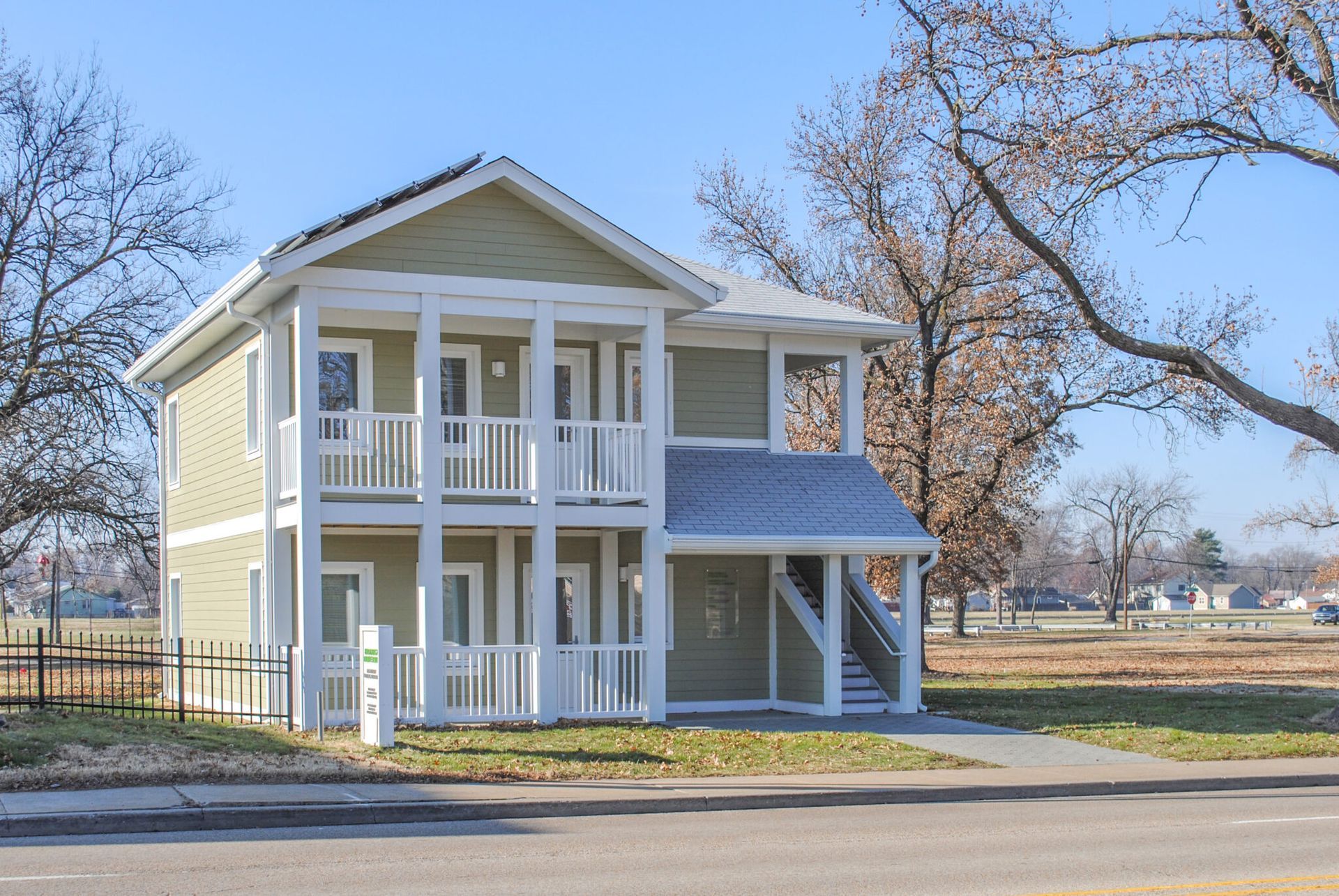 A large house with a lot of windows and balconies is sitting on the side of the road.