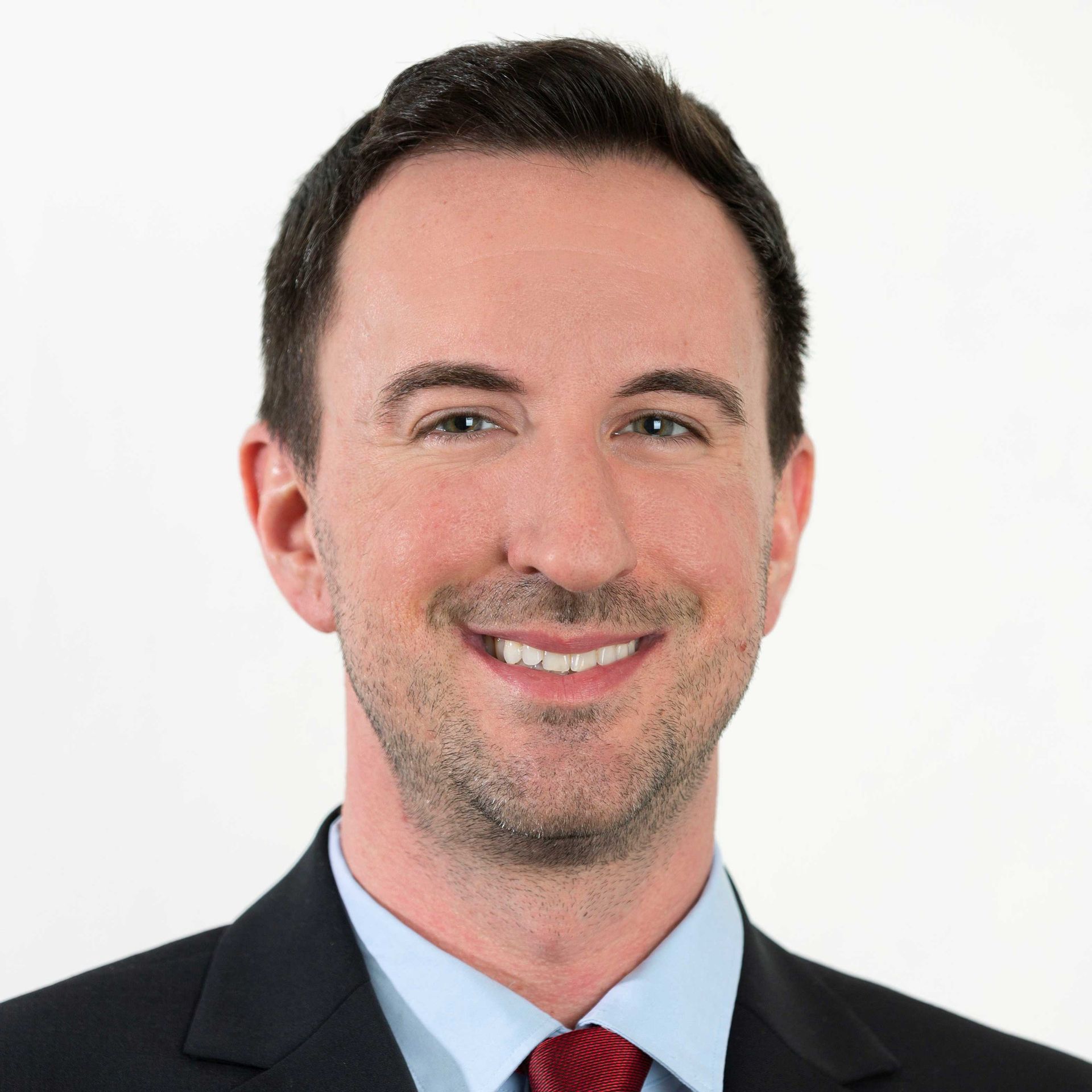 A man in a suit and tie is smiling for the camera