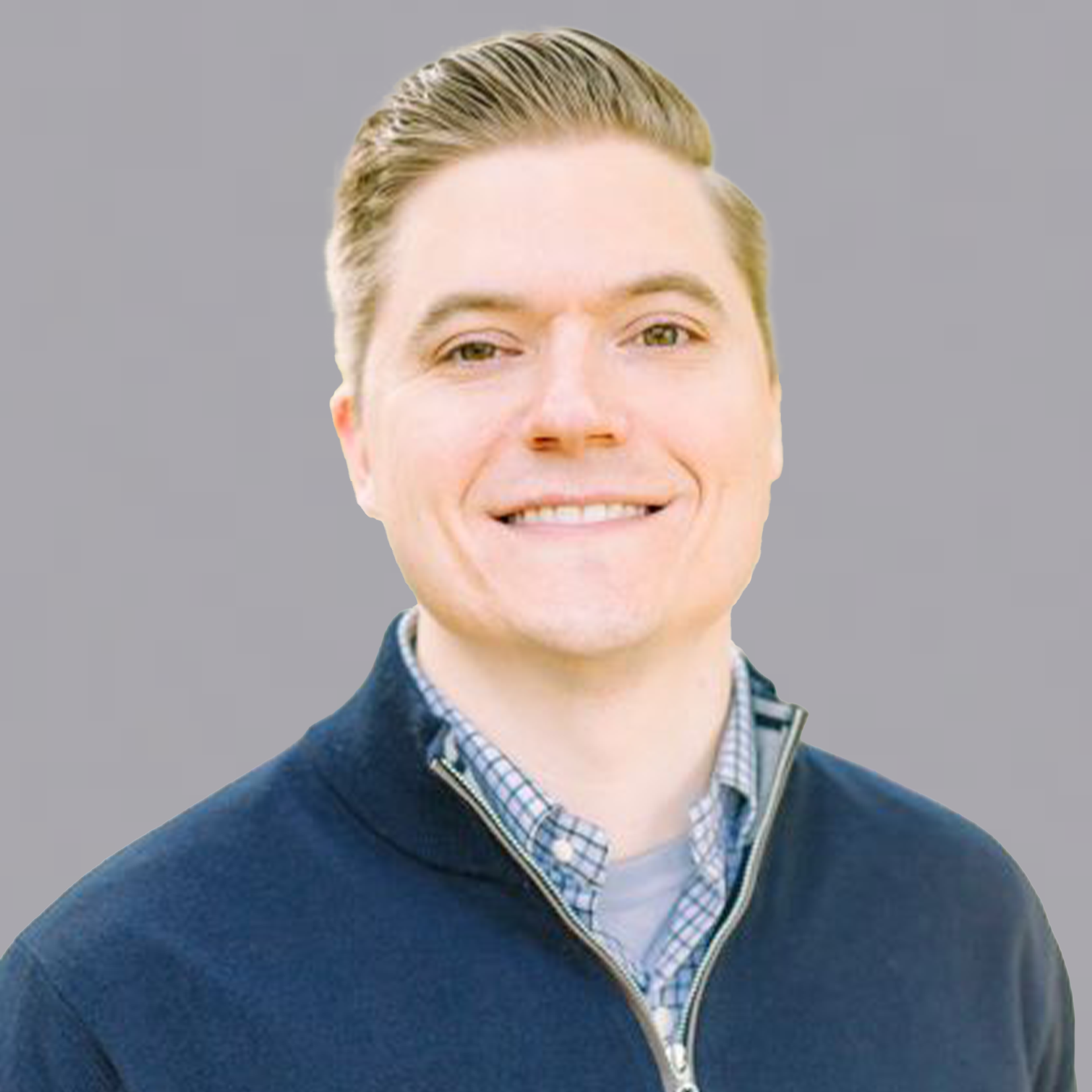 A man in a suit and white shirt is smiling in front of a sunset