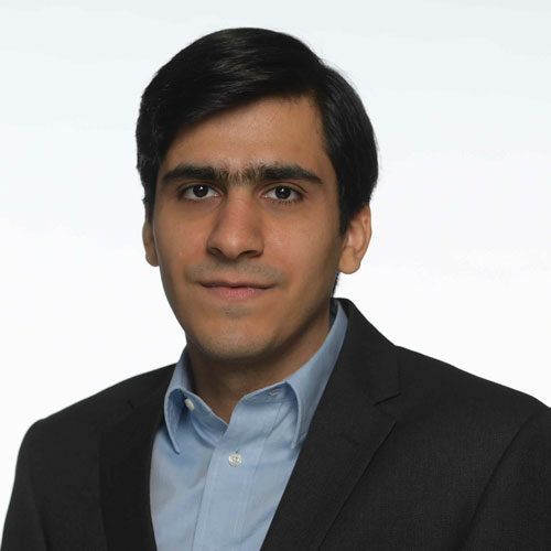 A man in a suit and blue shirt is smiling for the camera