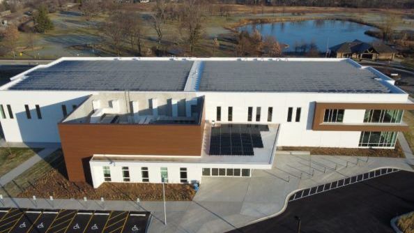 An aerial view of a large white building with a parking lot in front of it.