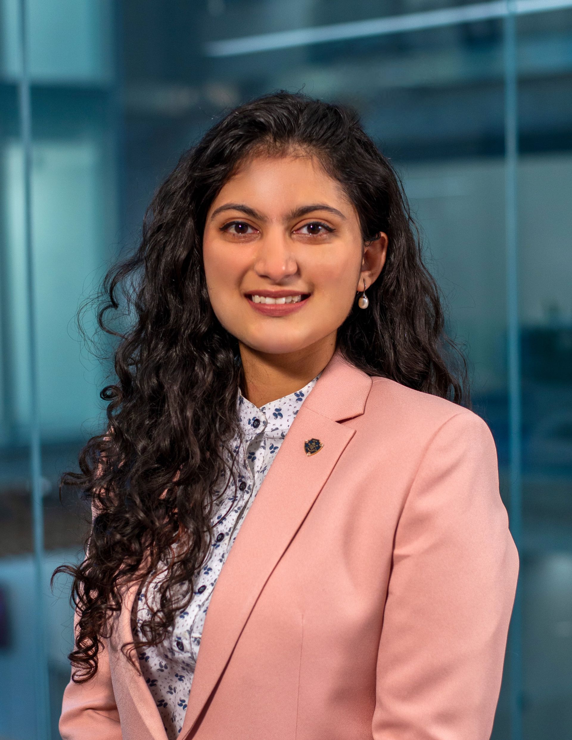 A woman in a pink jacket and white shirt is smiling for the camera.