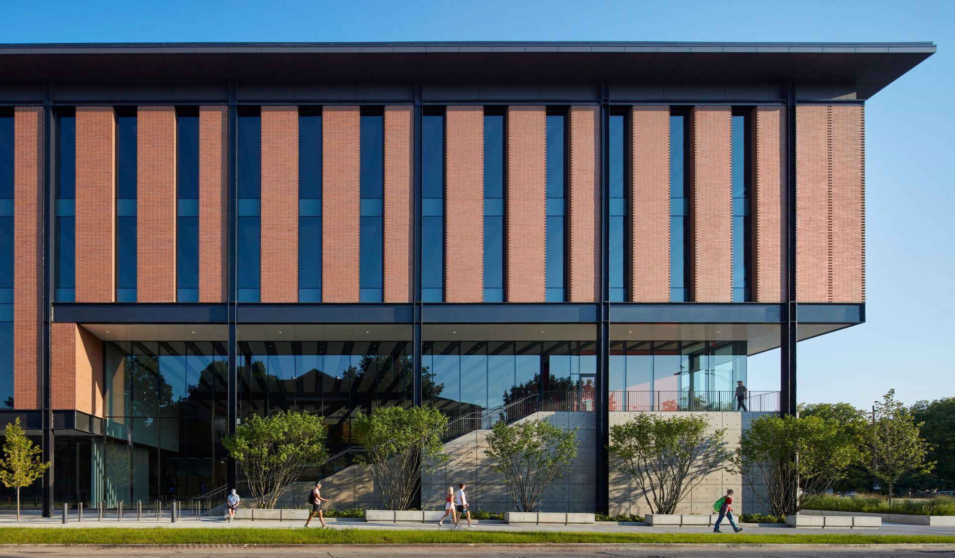 A large brick building with a lot of windows and people walking in front of it.