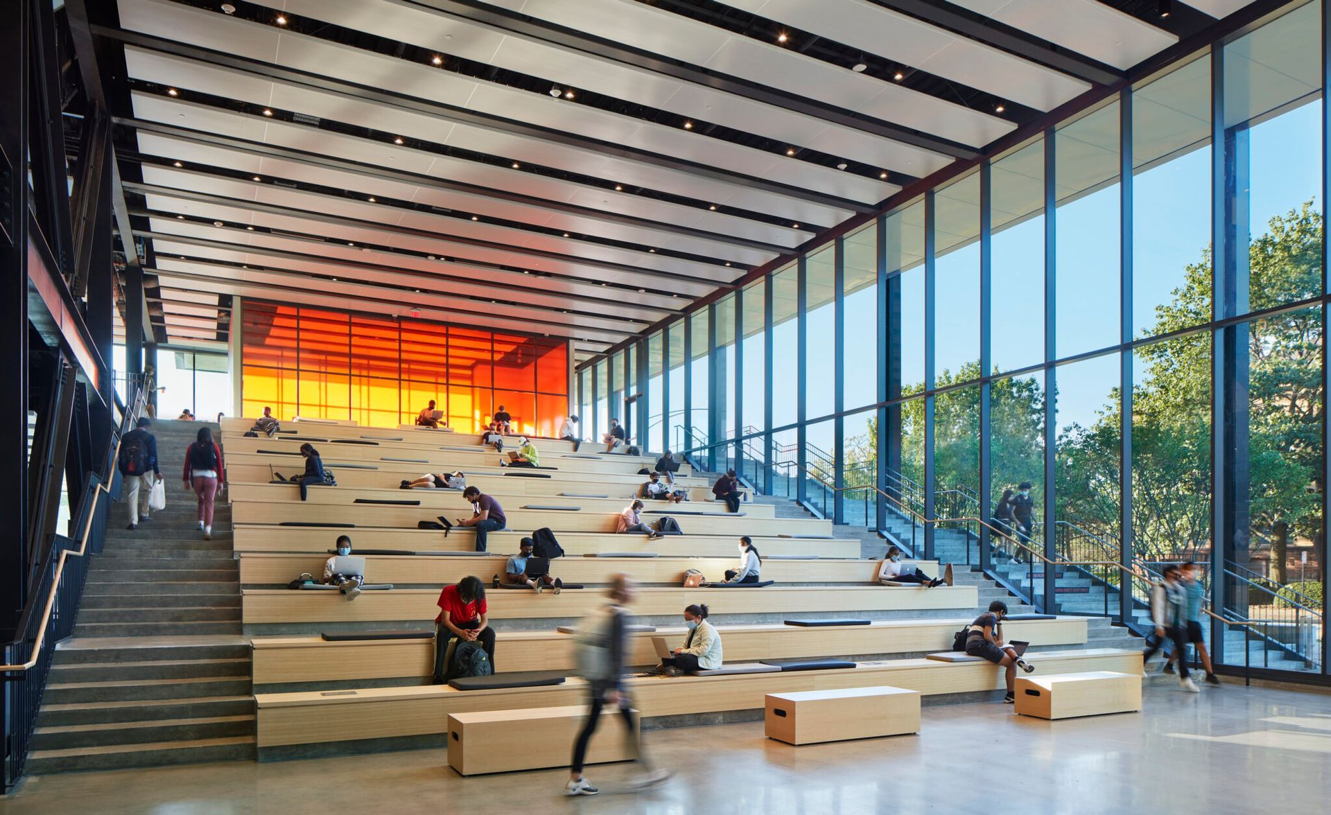 A group of people are sitting on wooden benches in a large building.