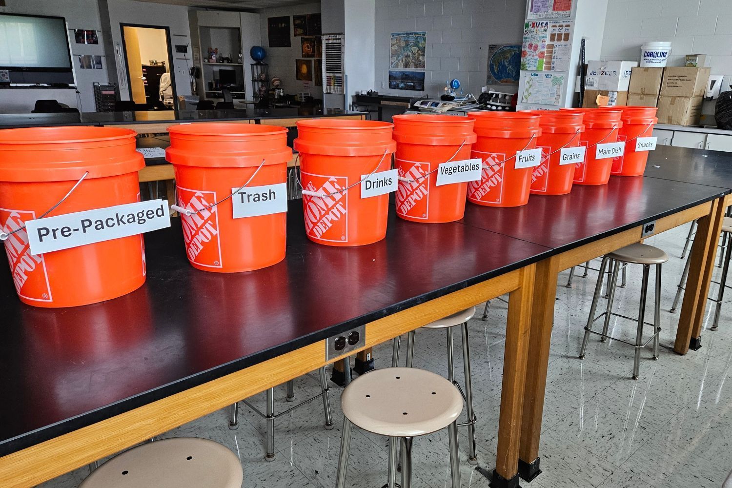 A row of orange buckets are lined up on a table
