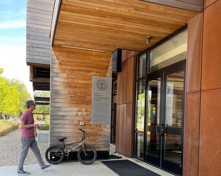 A man walking in front of a building with a bicycle parked in front of it