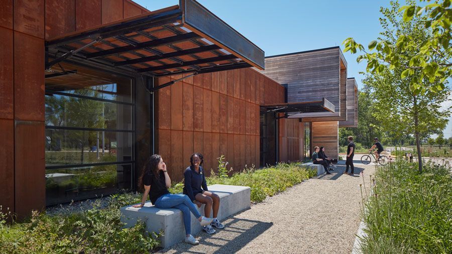 A group of people are sitting on benches in front of a building.