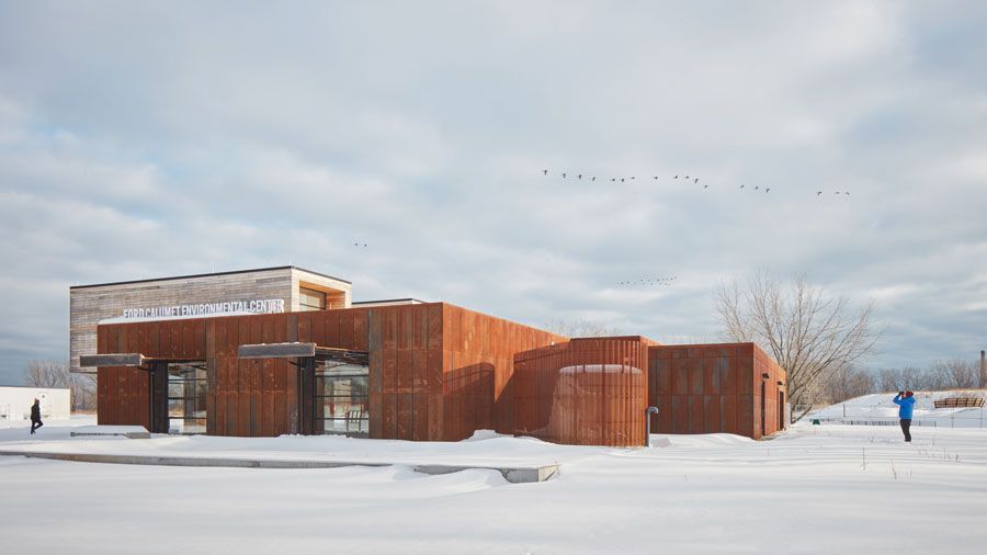 A large wooden building is sitting in the middle of a snow covered field.