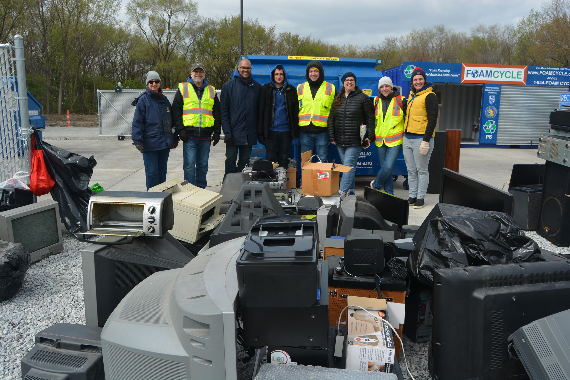 A group of people standing in front of a pile of electronics