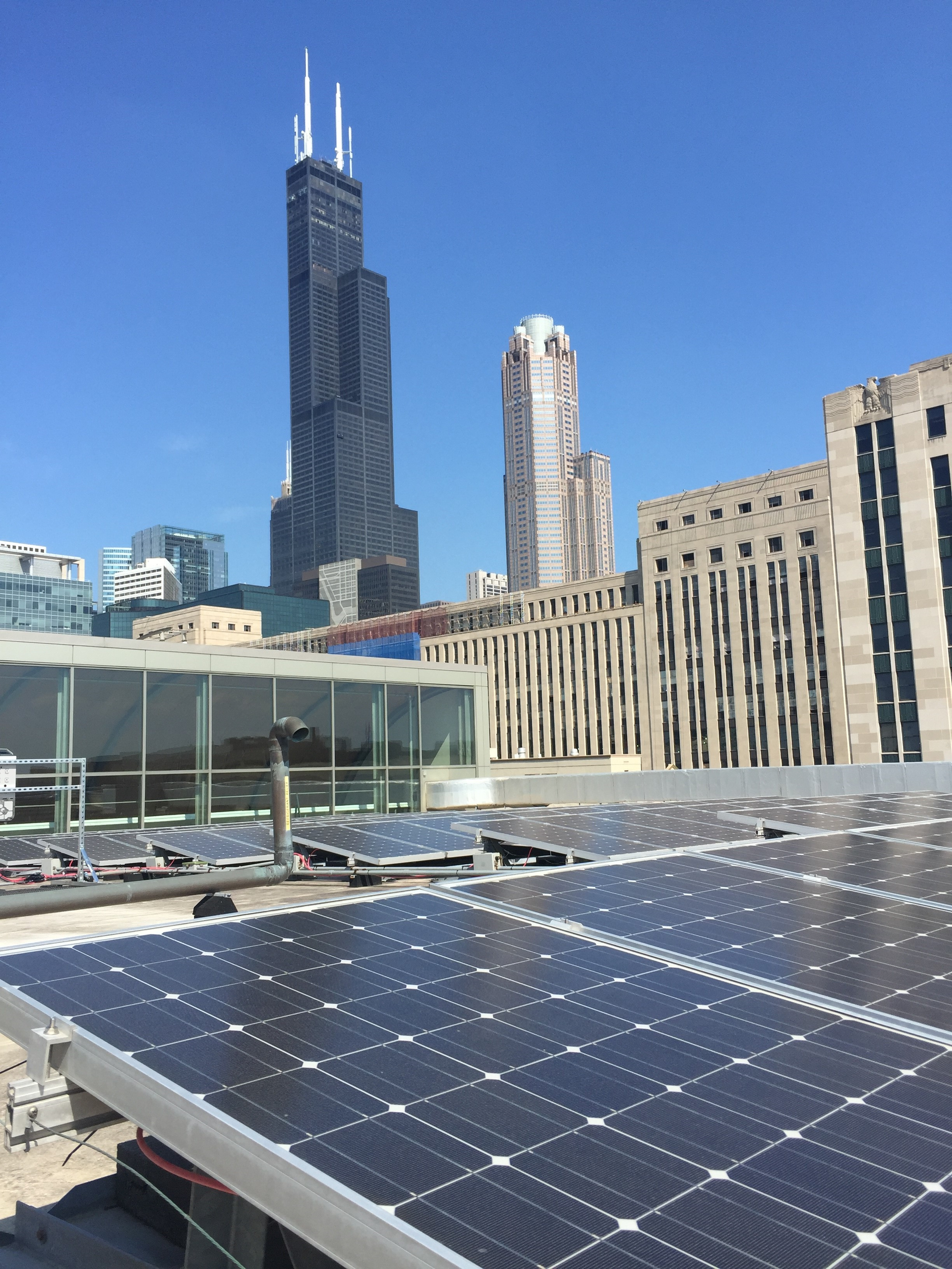 A row of solar panels on top of a building with a city skyline in the background