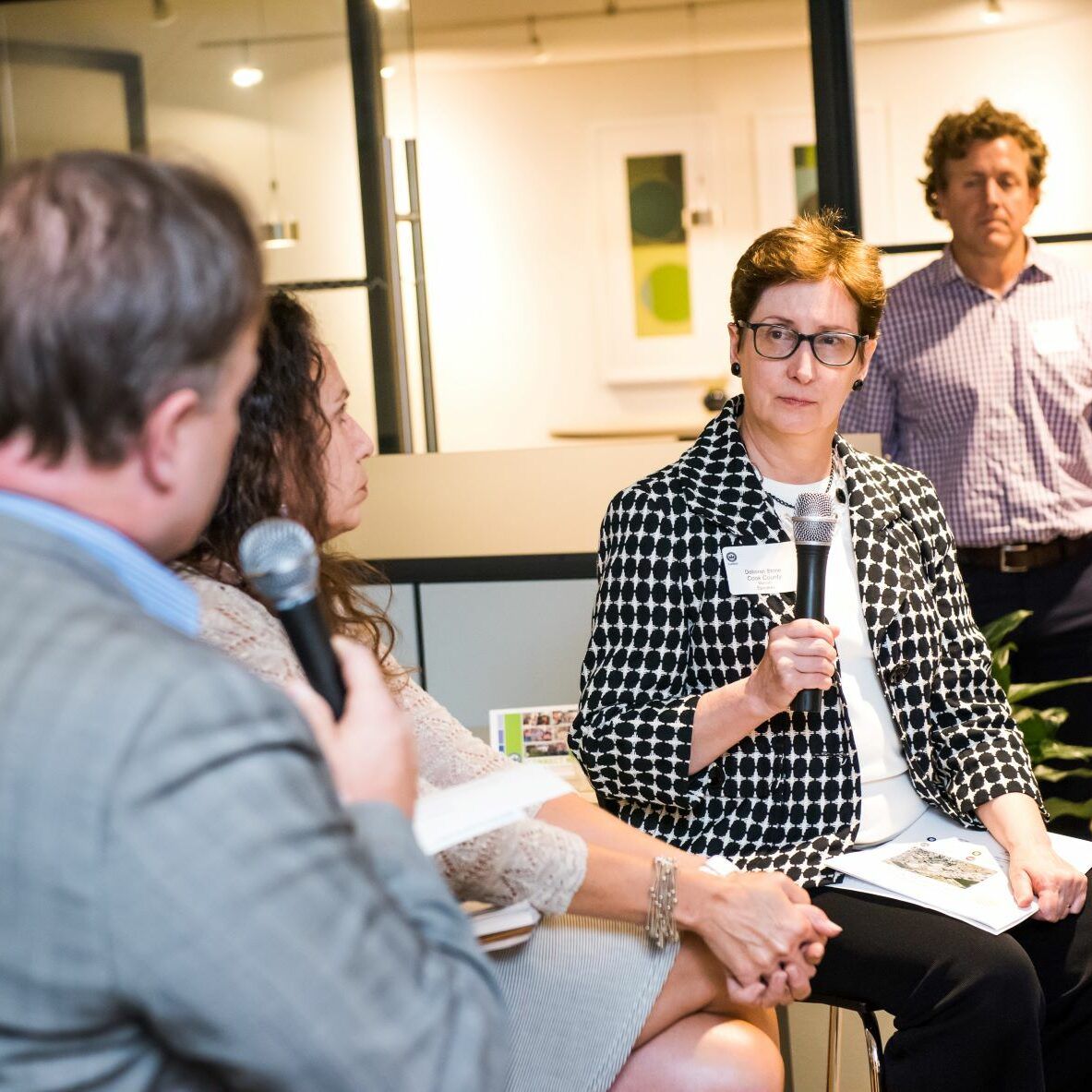 A woman is holding a microphone and talking to a group of people