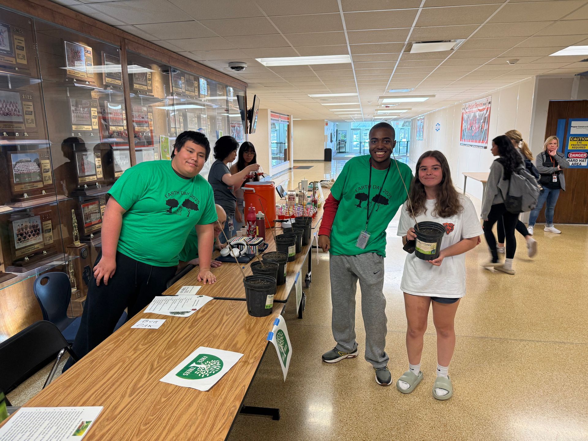 Students smiling and posing with tree saplings.