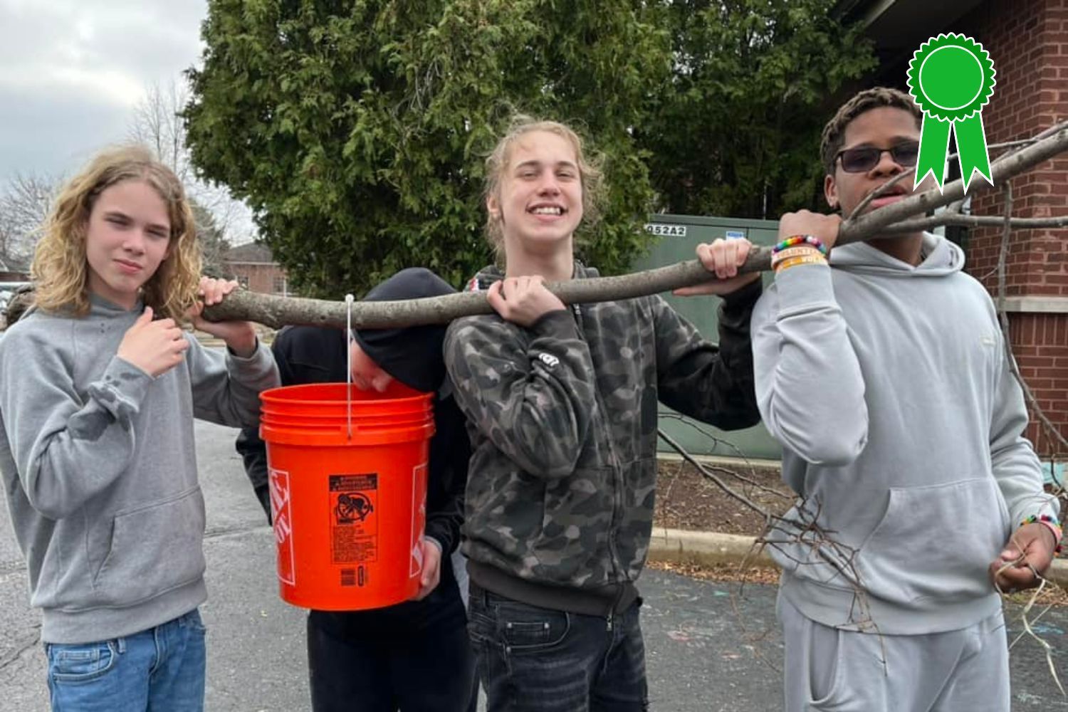 A group of young men are carrying a bucket and a stick.